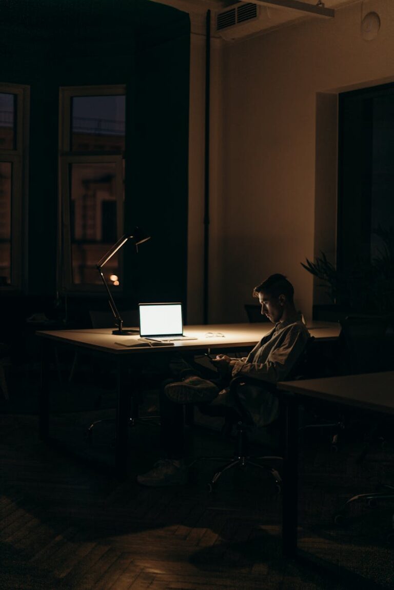 man in black and white stripe dress shirt sitting on chair in front of macbook