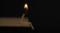 lighted matchstick on brown wooden surface